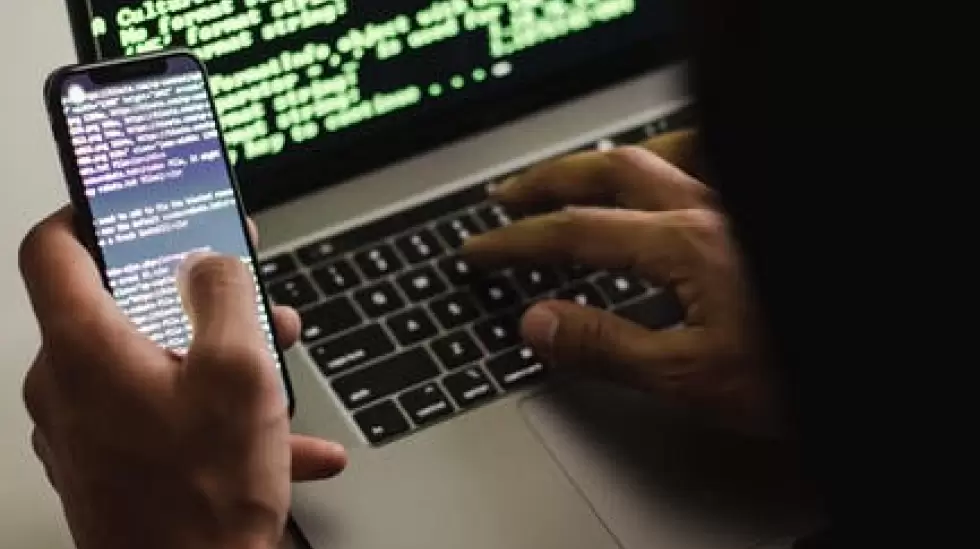 Hacker Irreconocible Con Smartphone Escribiendo En La Computadora Porttil En El