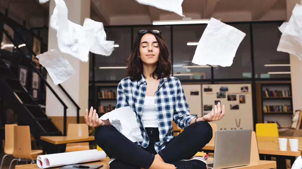 young-pretty-joyful-brunette-woman-meditating-on-table-surround-work-stuff-and-f