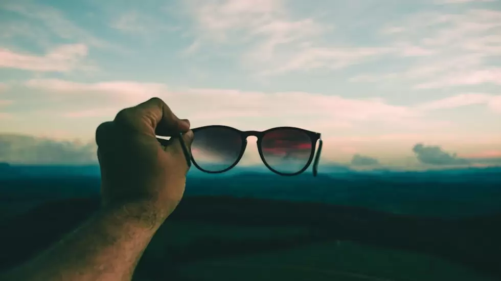 Persona Con Gafas De Sol Con Montura Negra Bajo Un Cielo Azul Y Nubes Blancas