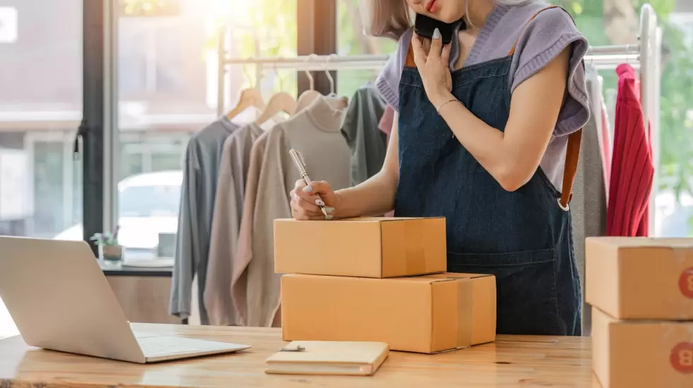 Una emprendedora gestiona pedidos en su tienda de ropa, reflejando la integraci