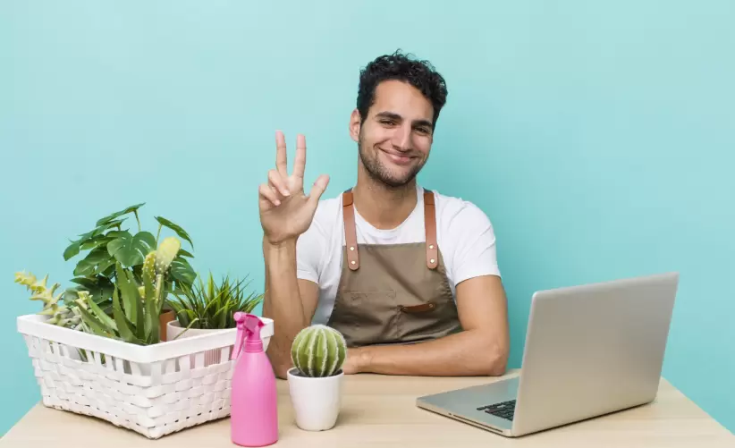 Joven emprendedor combina tecnología y pasión por las plantas, gestionando su negocio digital desde casa.