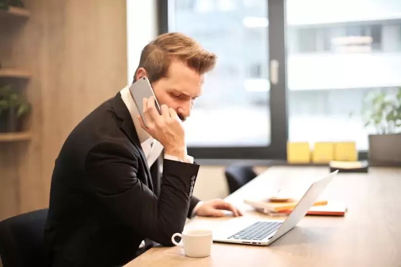Hombre Que Tiene Una Llamada Telefnica Frente A Una Computadora Porttil