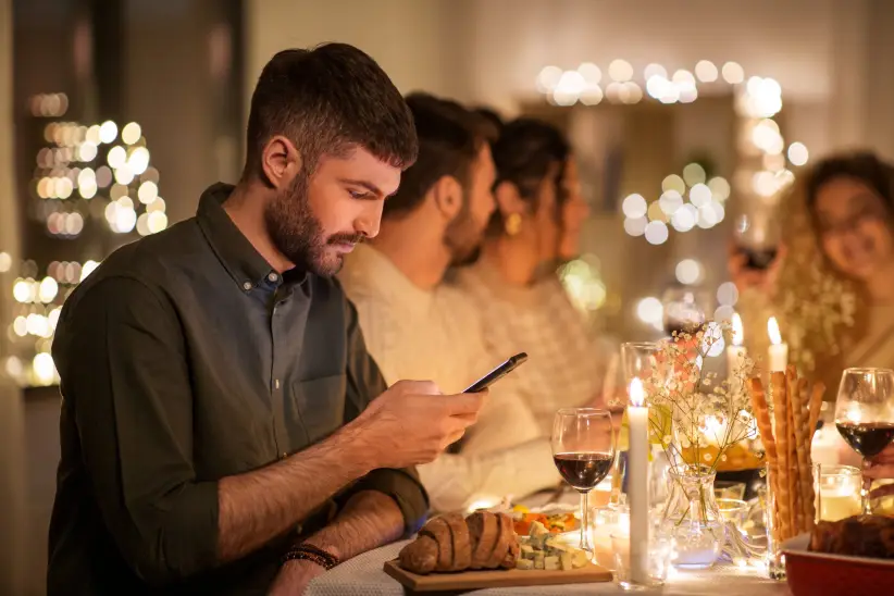 man-with-smartphone-dinner-party-with-friends