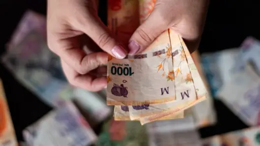 Una persona contando billetes de pesos argentinos, mostrando la moneda nacional. (Foto: Pexels)