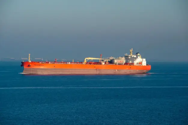 Un barco transportador de GNL de color naranja brillante navega por aguas tranquilas del mar en un día claro. (Foto: Pexels)