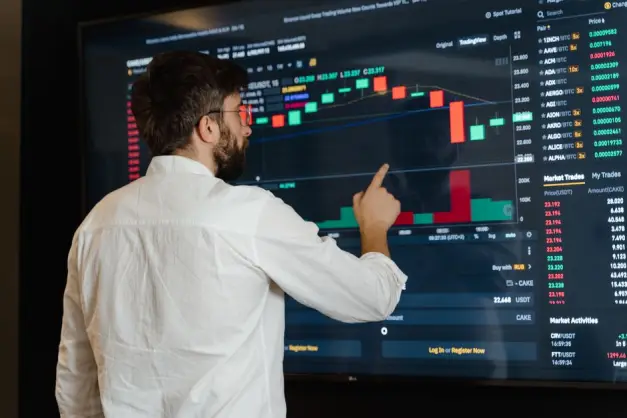 Un hombre analiza gráficos de criptomonedas en un monitor táctil en un entorno de oficina moderno. (Foto: Pexels)