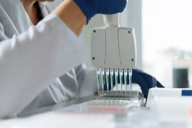 Un científico con bata de laboratorio utiliza una pipeta multicanal para el manejo de líquidos en un entorno de laboratorio. (Foto: Pexels)