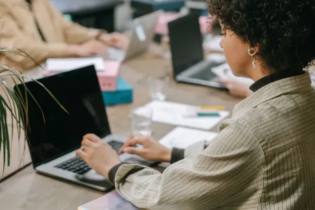 Una mujer profesional usando un portátil en un espacio de co-working, concentrada en su tarea. (Foto: Pexels)
