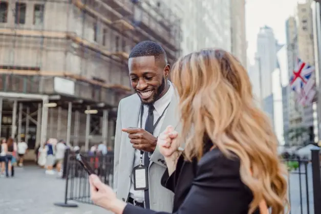 Dos profesionales se involucran en una conversación animada en una calle urbana, compartiendo ideas. (Foto: Pexels)
