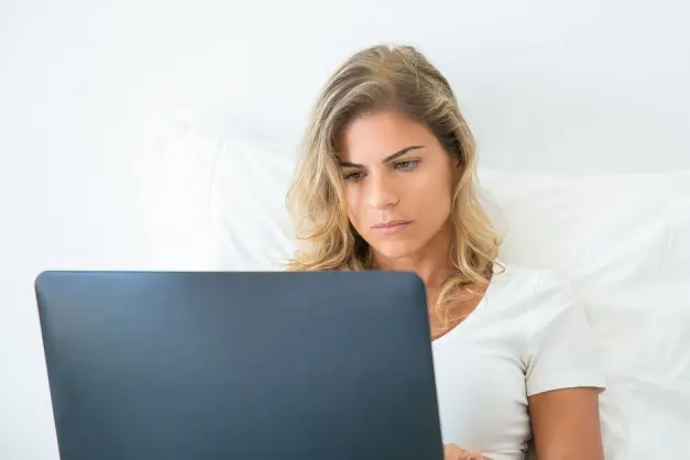 Una mujer trabajando atentamente en su portátil mientras está cómodamente sentada en casa, mostrando el estilo de vida del trabajo remoto. (Foto: Pexe