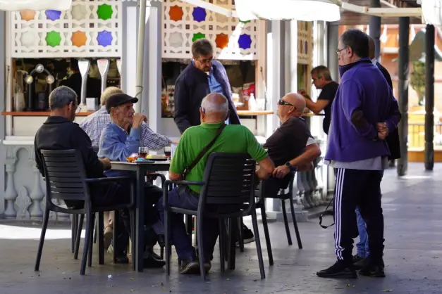 Grupo de hombres ancianos socializando en una cafetería al aire libre, disfrutando de bebidas y conversación. (Foto: Pexels)