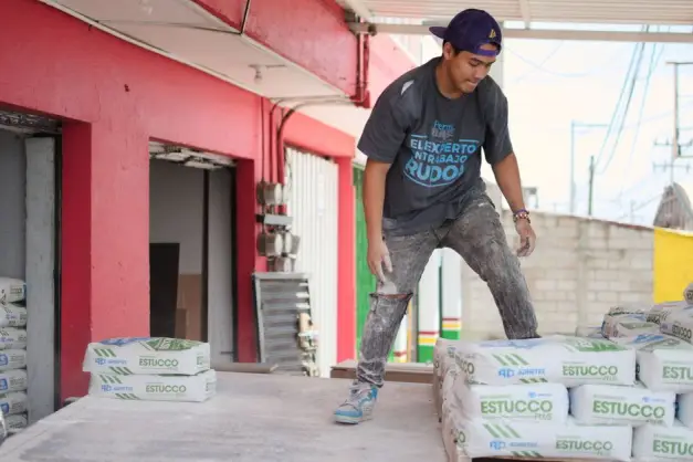 Joven trabajador de construcción descargando bolsas de yeso en un sitio de trabajo. (Foto: Pexels)