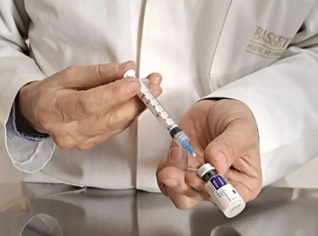 Veterinario preparando una jeringa con vacuna de un vial en un entorno médico. (Foto: Pexels)