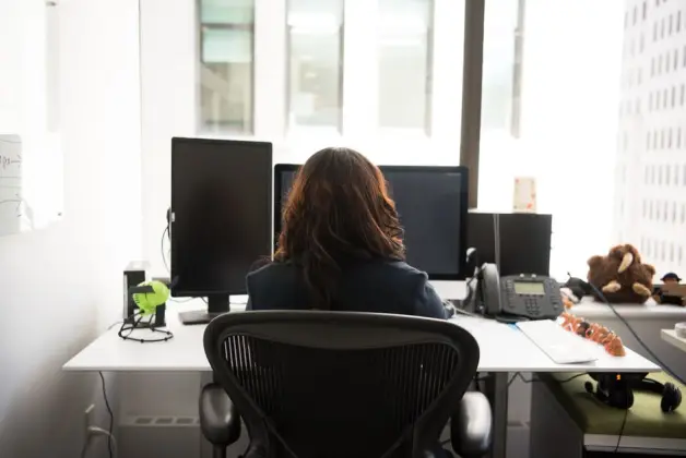 Mujer trabajando en un escritorio moderno con tecnología y vista de la ciudad. (Foto: Pexels)