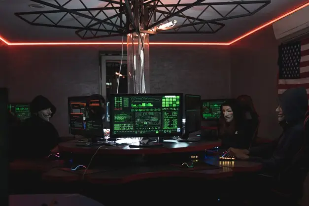 Equipo de hackers con máscaras de Guy Fawkes programando en una habitación oscura con ordenadores. (Foto: Pexels)