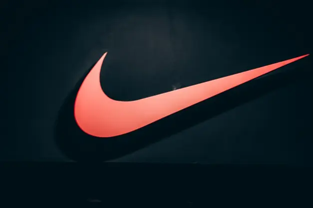 Logotipo vibrante del swoosh rojo de Nike exhibido sobre un fondo oscuro y minimalista que simboliza deportes y estilo de vida. (Foto: Pexels) - Foto: Pexels.