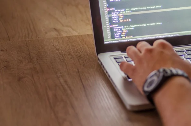 Primer plano de una persona programando en un portátil, mostrando conceptos de desarrollo web y programación.
