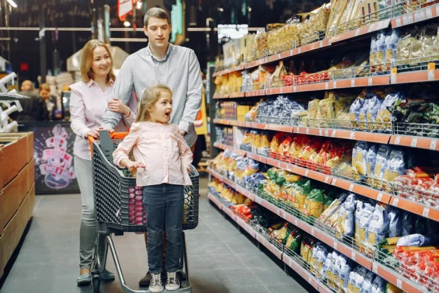 Una familia alegre disfrutando de un día de compras en el pasillo de un supermercado.