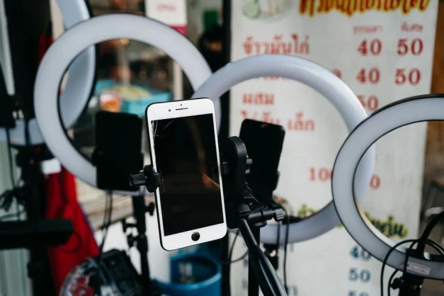 Un smartphone moderno montado en un trípode rodeado de luces de anillo, ideal para vlogging o creación de contenido.