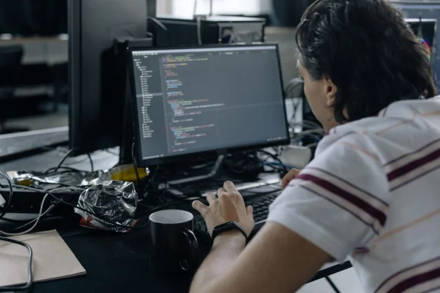 Hombre enfocado en programar en su estación de trabajo en una oficina moderna.