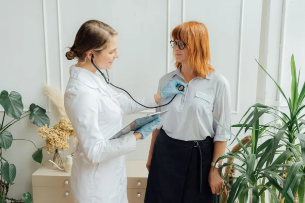 Consulta médica con un doctor utilizando un estetoscopio para examinar al paciente en interiores.