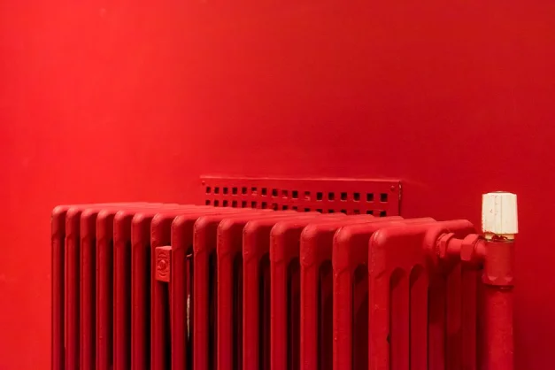 Un radiador rojo vibrante contra una pared a juego captura el diseño de interiores minimalista y moderno.