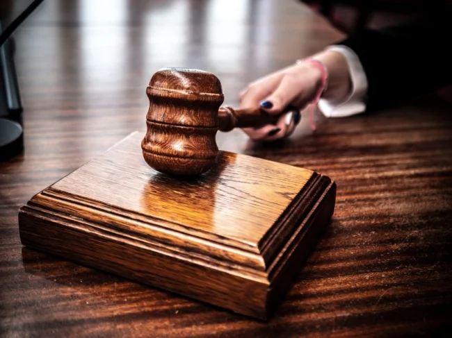 Primer plano de un mazo de madera sobre el escritorio de un juez, símbolo de la justicia.