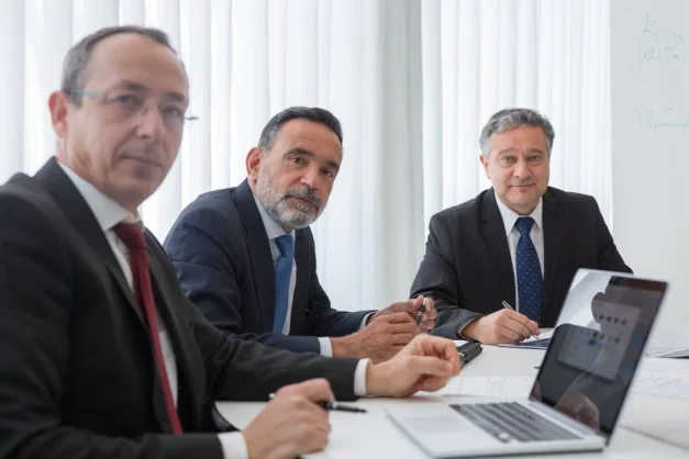 Ejecutivos senior en trajes realizando una reunión en un entorno de oficina.