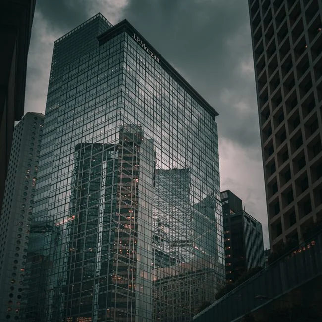 Un imponente rascacielos de vidrio con reflejos de la ciudad en un día nublado.