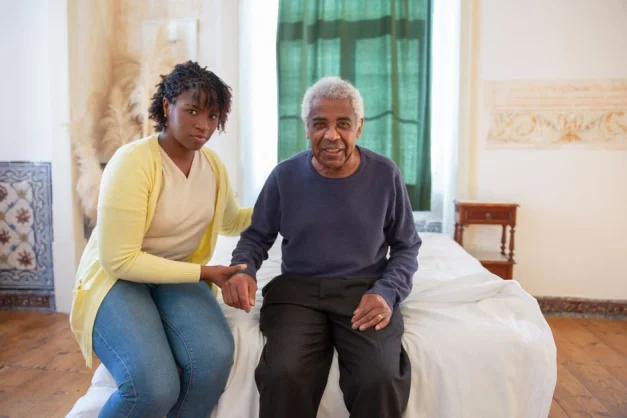 Hija apoyando a su padre anciano en una habitación brillante y acogedora, llena de amor y calidez.