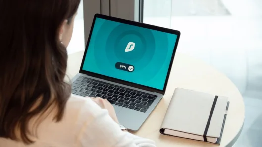 Una mujer trabajando en un portátil con un ícono de VPN en pantalla para una navegación en línea segura.