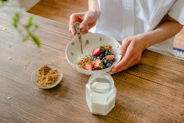 Un vibrante bol de yogur casero con fresas, arándanos y nueces trituradas, perfecto para un desayuno saludable.