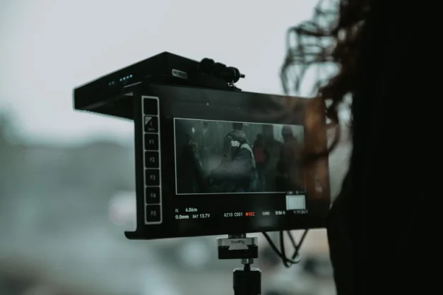 Un primer plano de equipo de filmación profesional capturando una escena al aire libre.